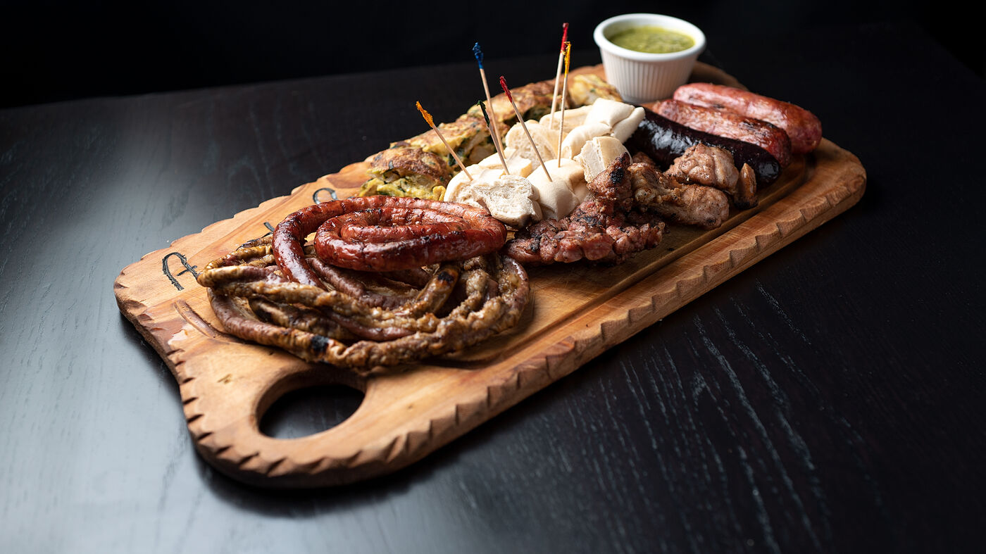 Picada de chorizo, morcilla, queso y achuras servida sobre tabla de madera