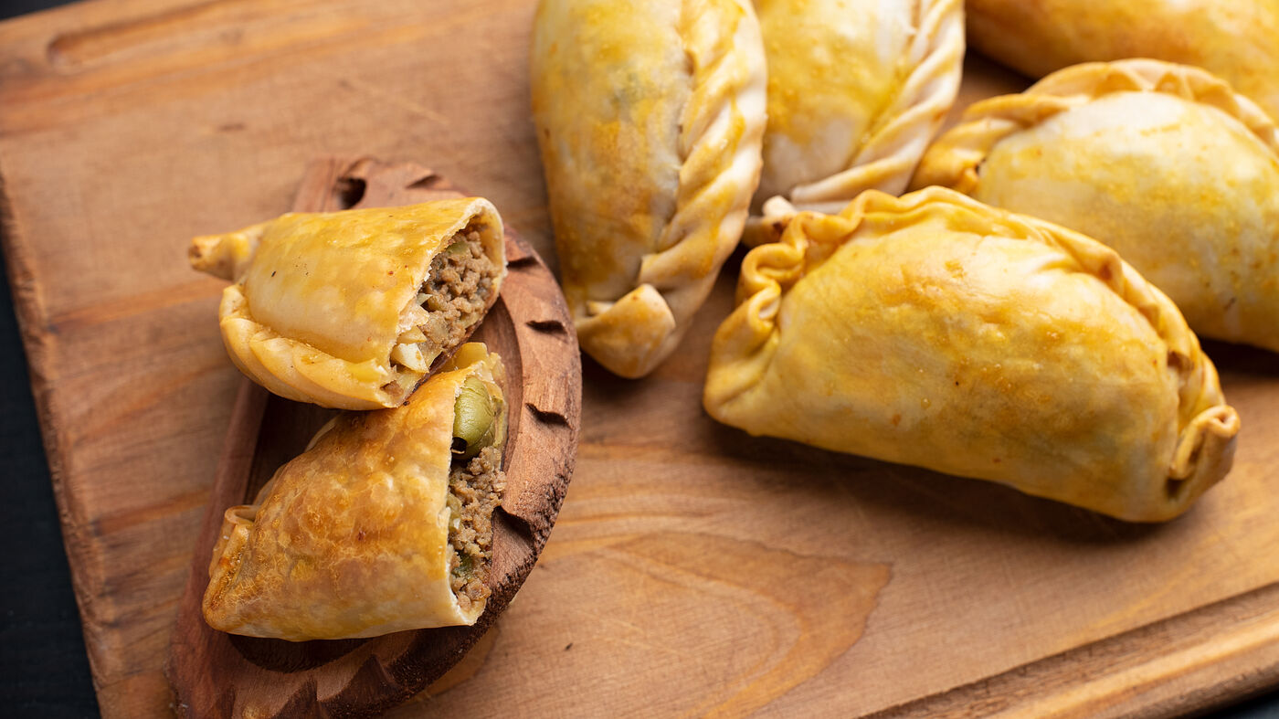 Empanadas argentinas caseras recién horneadas sobre tabla de madera