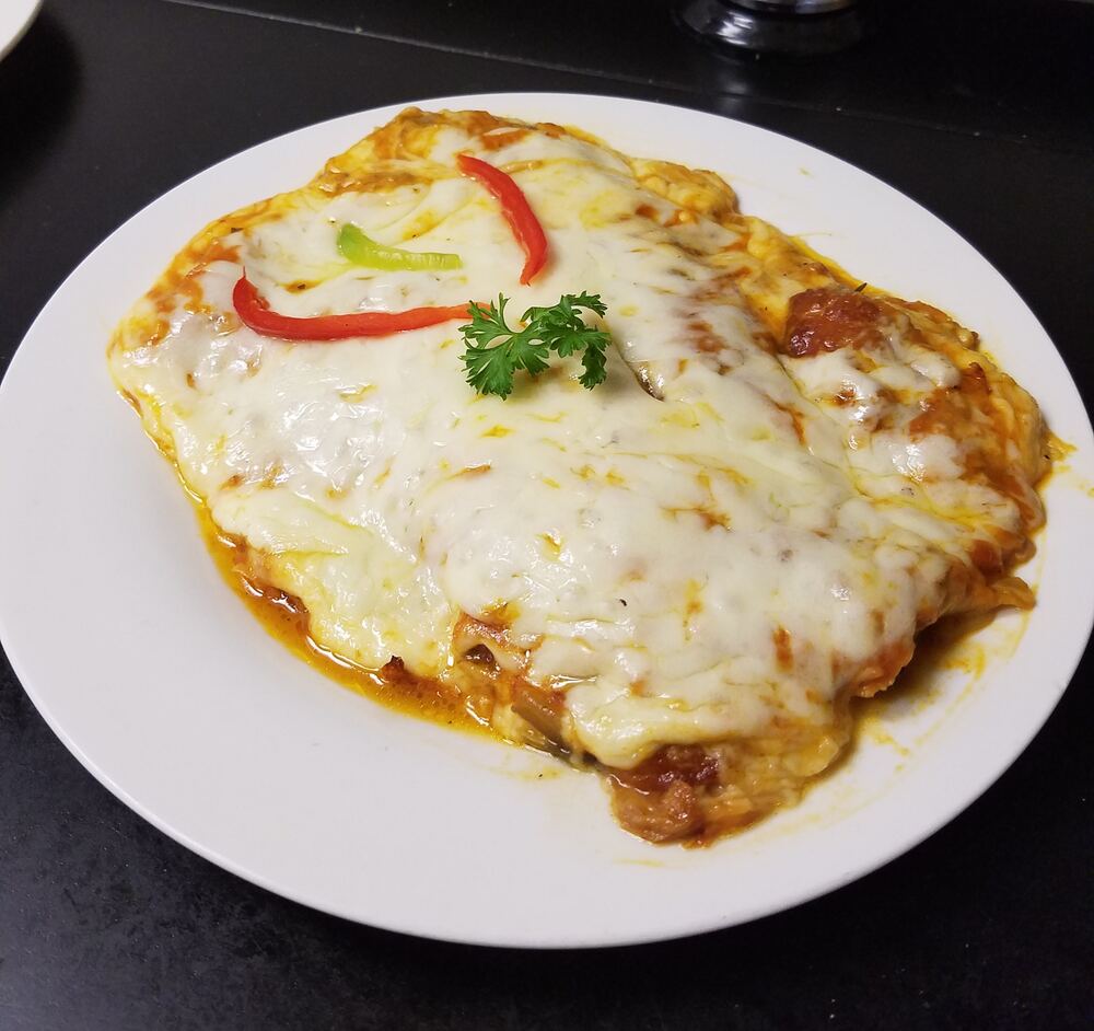 Milanesa napolitana cubierta de queso derretido y salsa de tomate en plato blanco